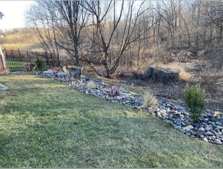 River-rock dry creek bed running along the edge of a lawn to carry water away