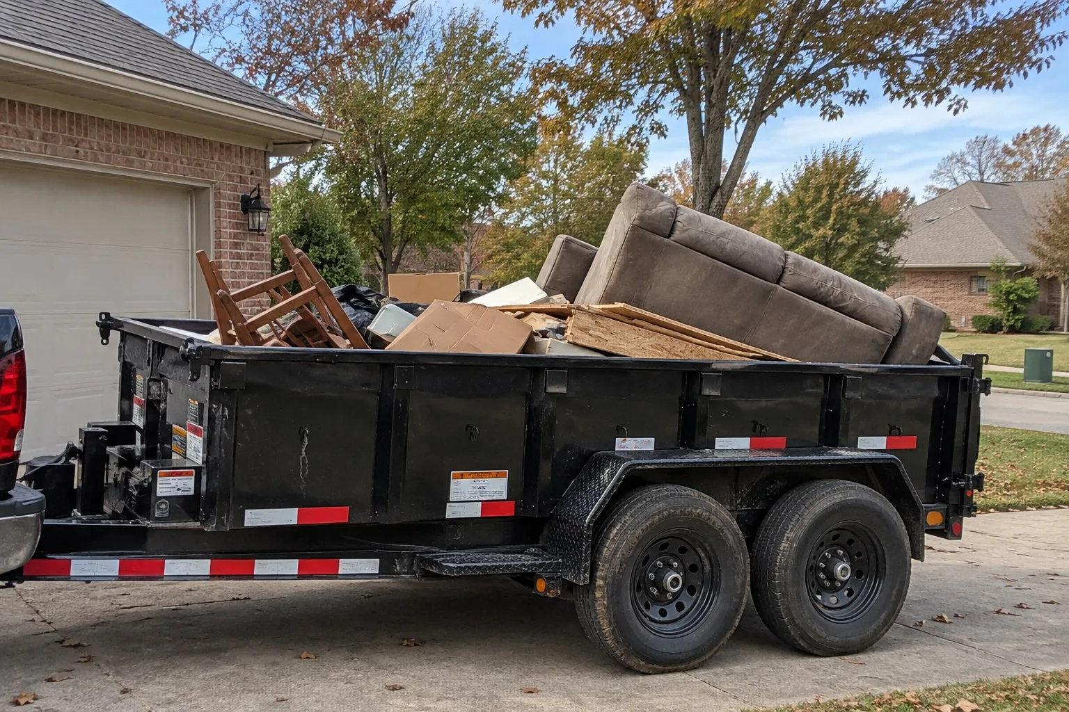 Illustrative image of an old sofa, boards and boxes piled in a black dump trailer